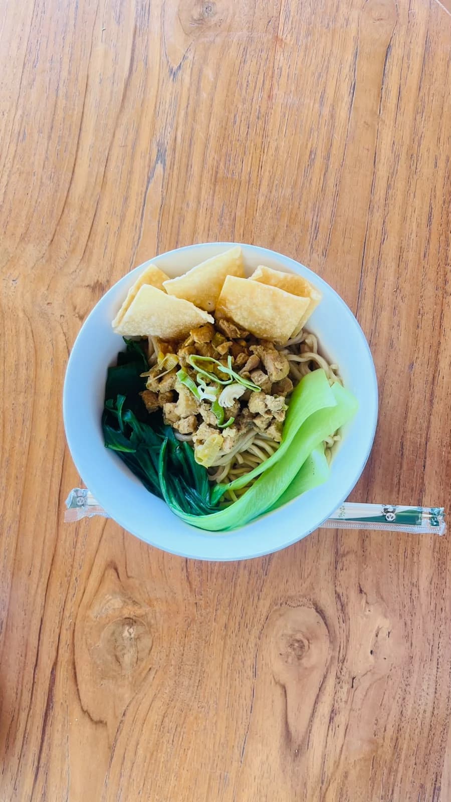 Mee Yamin topped with chicken, greens and crispy dumpling skin